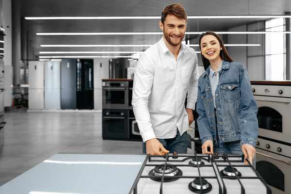 A smiling couple in front of a gas range